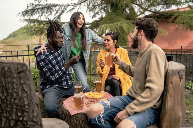 A diverse group of friends shares drinks and laughs while enjoying a casual hangout in a park setting