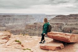 Female relaxing on cliff and admiring picturesque view