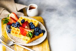 Waffle breakfast with blueberries & strawberries served with syrup on the side with copy space