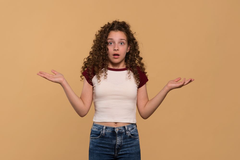 Young girl with arms open, showing confused expression