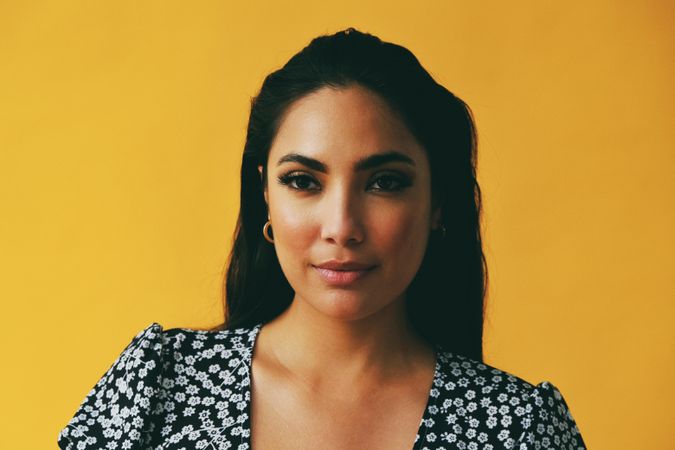 Headshot of Hispanic woman looking away from camera in yellow room, copy space