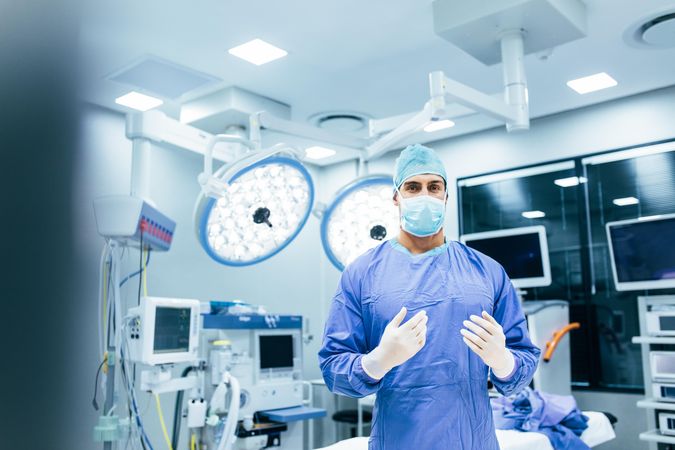 Portrait of male surgeon standing in operating room, ready to work on a patient