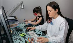 Woman teleworking with her daughter drawing