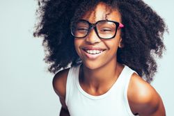 Studio portrait of laughing girl wearing large glasses