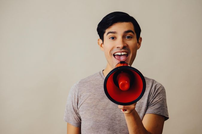 Hispanic male speaking through red loudspeaker