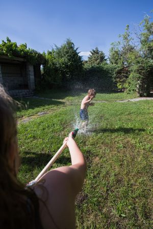 Little kids in swimwear having fun with splashing water