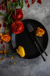 Rustic table setting with dark plate and fresh flowers