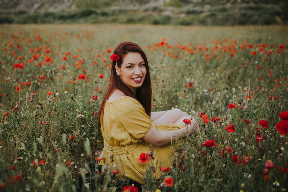 Woman sitting in field with poppies and daisies