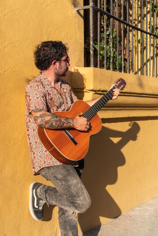 Young man playing guitar on the city streets at sunset