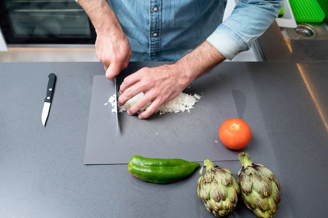 Man fine cutting onion on board with knife