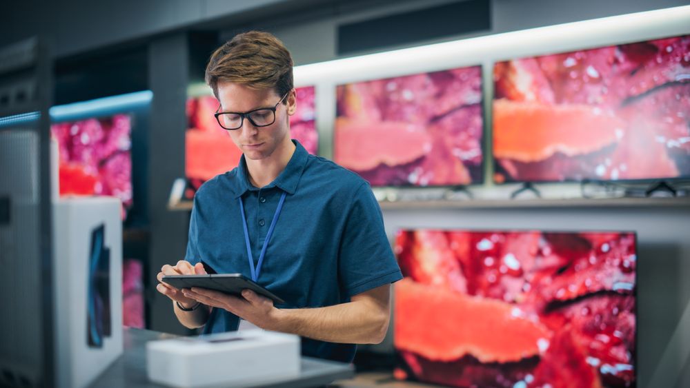 Young Productive Salesperson in Home Electronics Store Working on Tablet