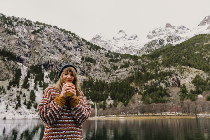Woman on seat near wonderful lake between hills in snow