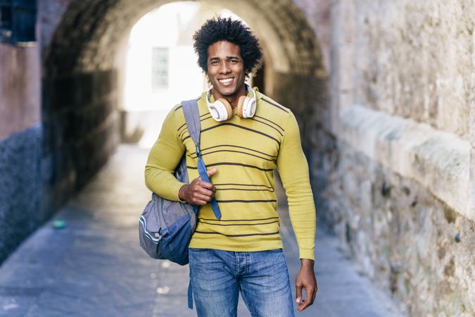 Man walking through Spanish city with backpack and headphones