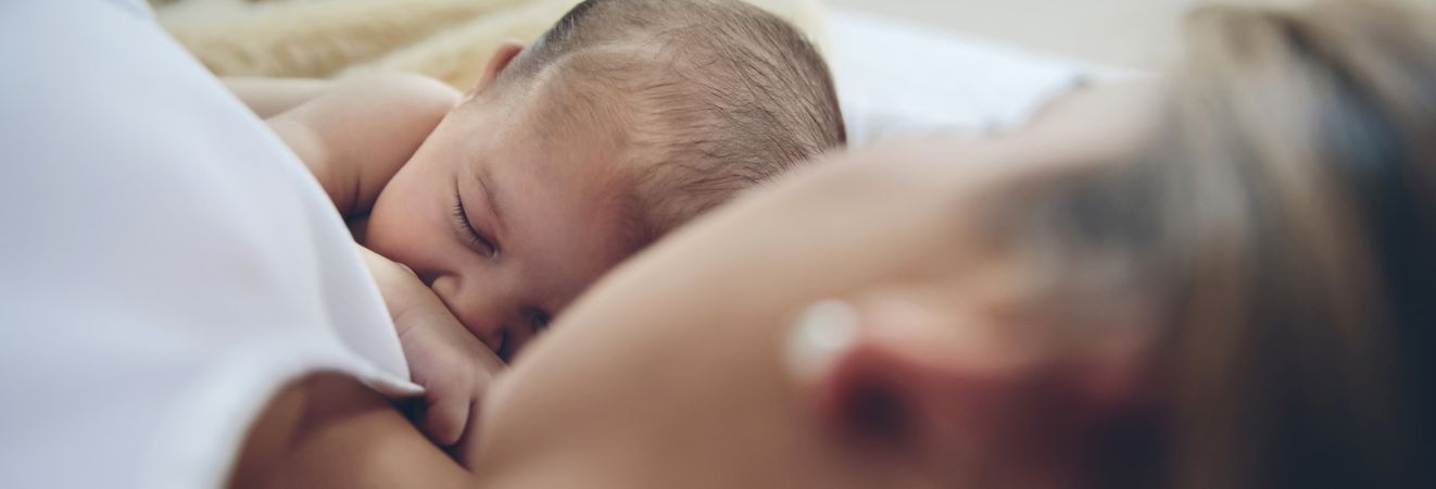 Newborn lying on the bed with her mother