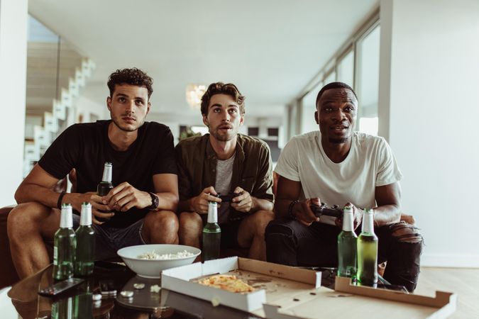 Three friends seriously focused on video games