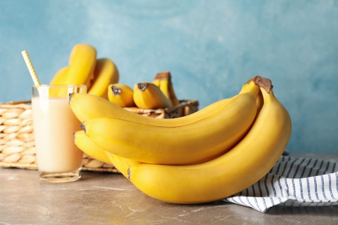 Basket, bananas and juice against blue background. Fresh fruit
