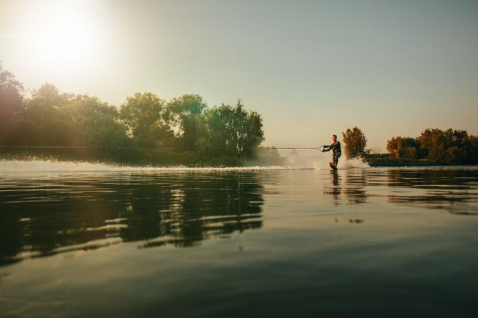 Man water skiing on lake behind a boat
