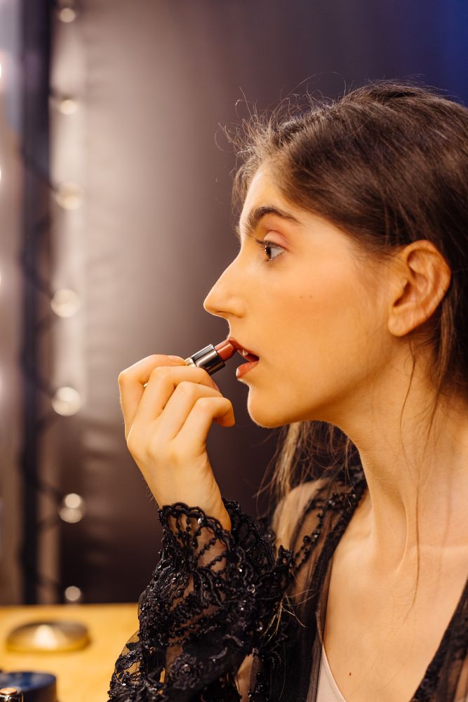 Glamorous female applying lipstick