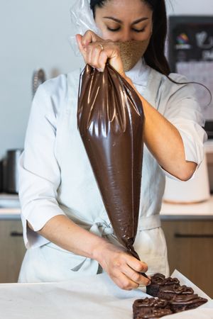 Woman adding chocolate cream on cakes