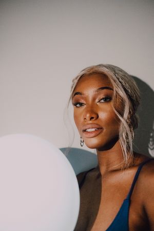 Black adult woman with illuminated balloon in darkness looking at camera