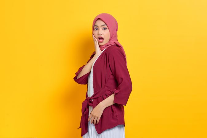 Scared woman in red headscarf with hand on cheek