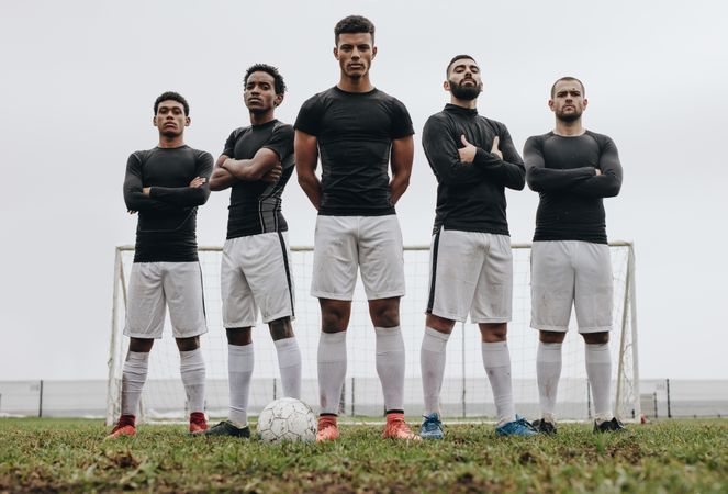 Soccer players standing together with arms crossed on a soccer field