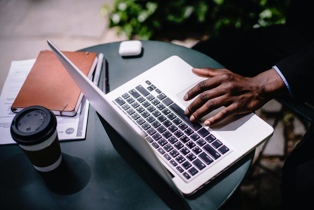 Cropped image of person working on their computer in a coffee shop