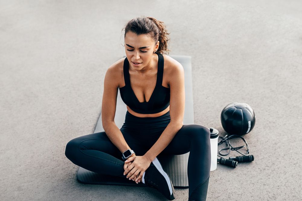 Woman sitting on yoga mat before a workout