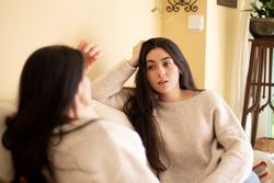 Young woman talking with worried face with her mother sitting on the sofa at home.