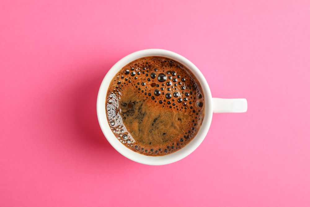Cup of coffee on color background, space for text