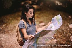 Female hiker in forest reading a map 0gdz75
