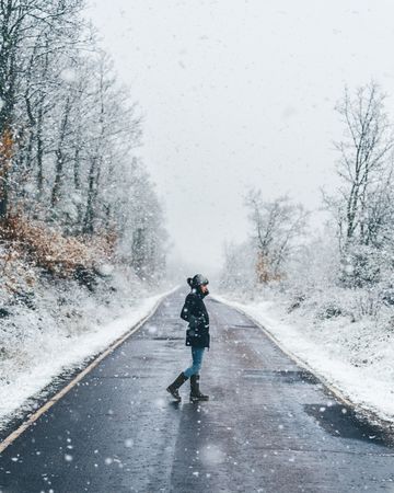 Young woman crossing winter country road