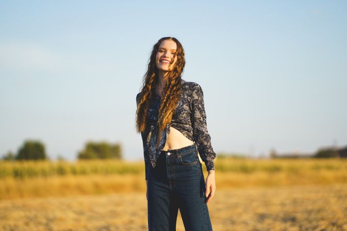 A Joyful Young Woman Smiling Brightly in a Beautiful Sunlit Field Glowing with Light