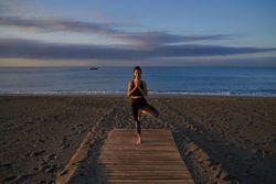 Hispanic woman practicing Tree pose on shore