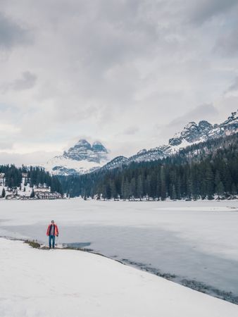 Unrecognizable person standing in snow surrounded by forest and mountains