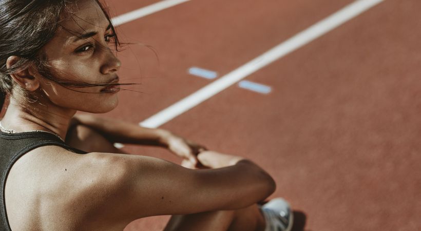 Close-up of a fit woman after run sitting on race track