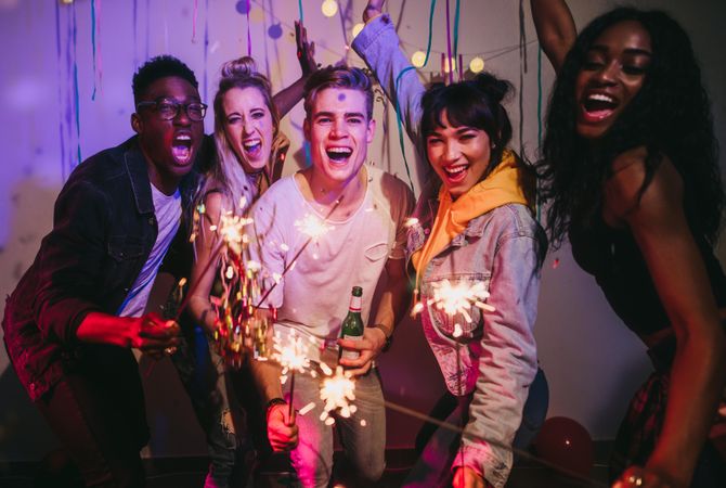 Young people smiling and celebrating with sparkles at a house party