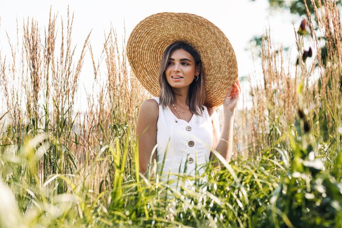 Woman in straw hat standing outside in pond grass