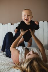 Mother playing with baby on bed