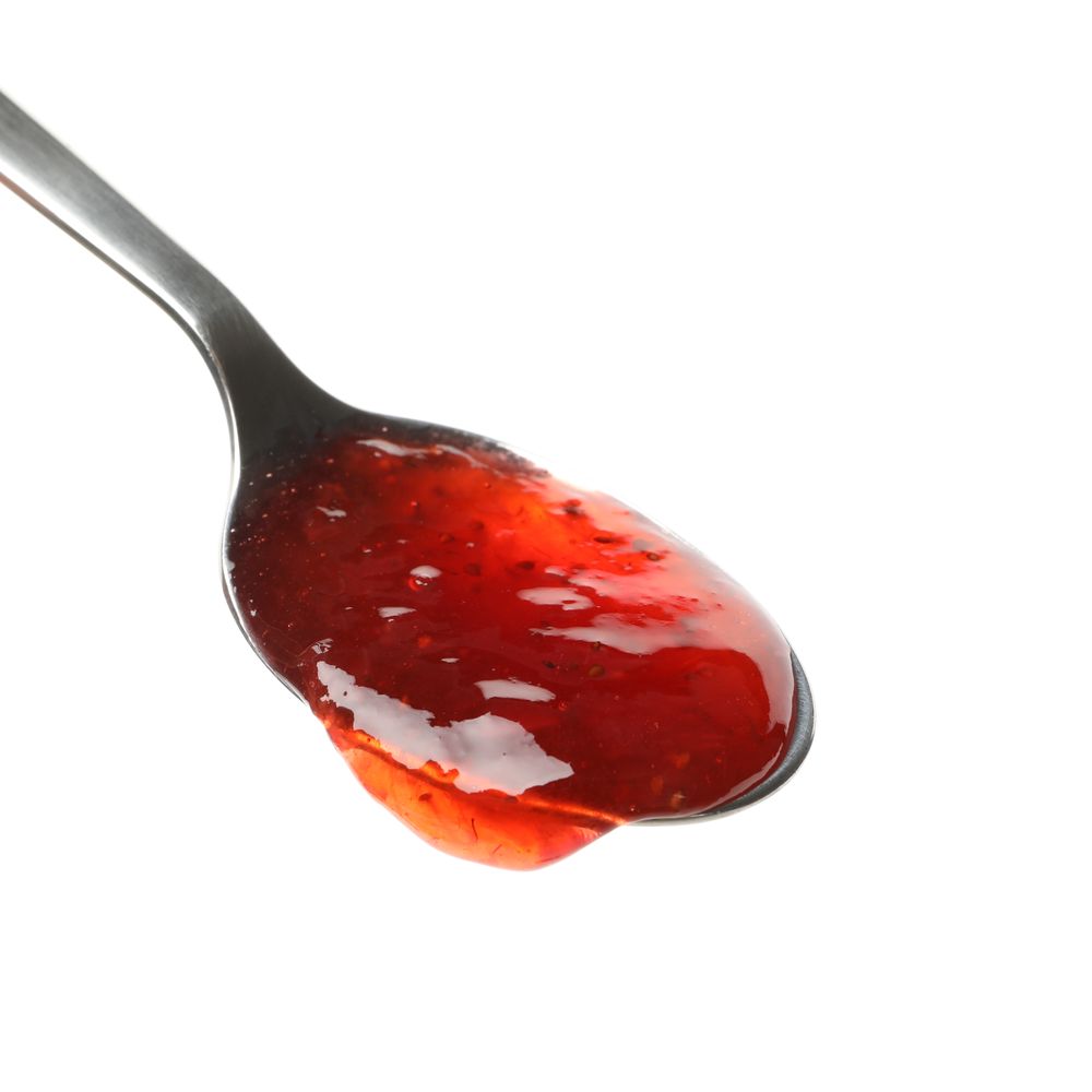 Spoon with strawberry jam isolated on plain background