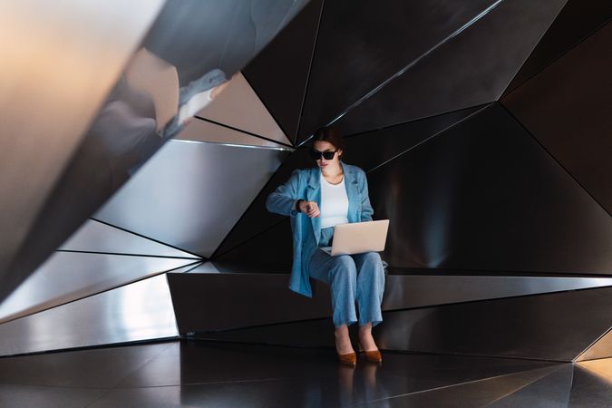 Woman with laptop checking time in modern studio