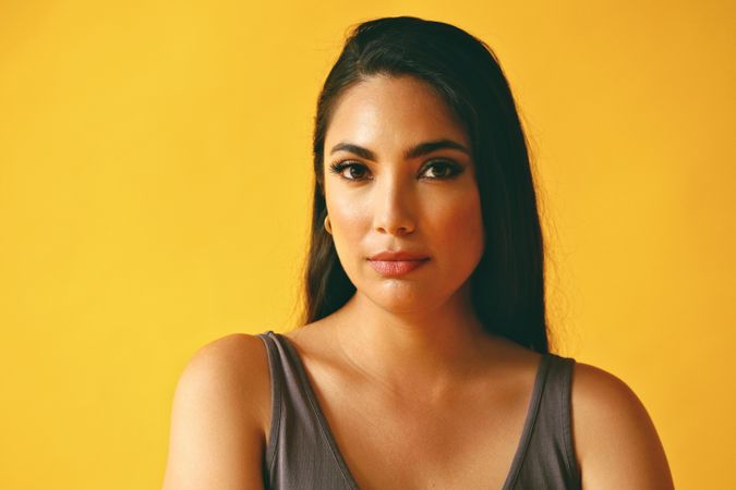 Serious Hispanic woman looking away in yellow room