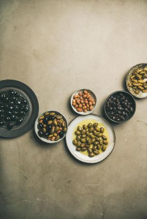 Olives in bowls on concrete background, copy space