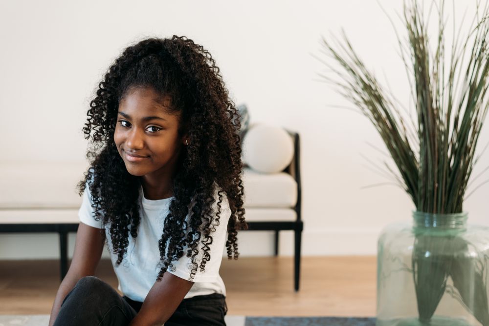 Beautiful young Black teenage girl sitting in a rug