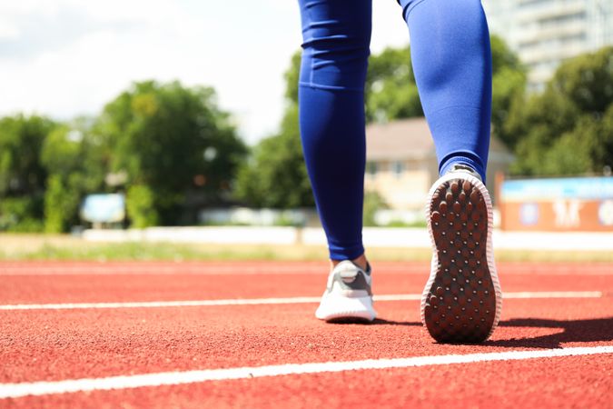 Girl walking on red athletic track, space for text