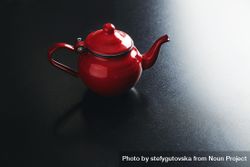 Shiny red tea pot on dark table 5ango4