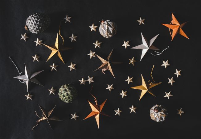 Flat-lay of colorful paper toy decorative stars, with pine cones and baubles