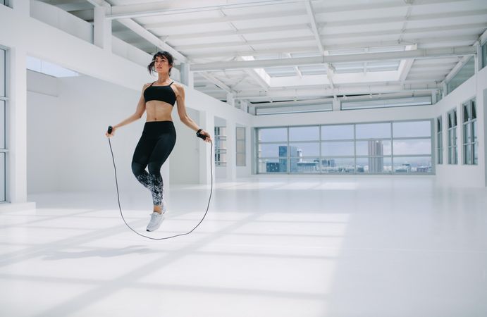 Woman exercising and jumping rope inside fitness studio