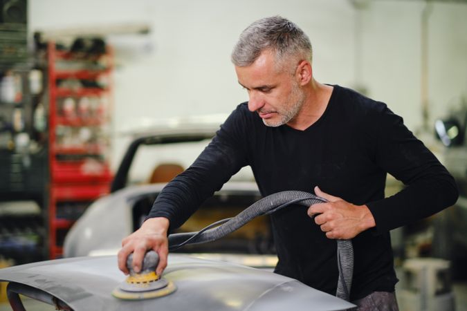 Mechanic grinding paint from car detail