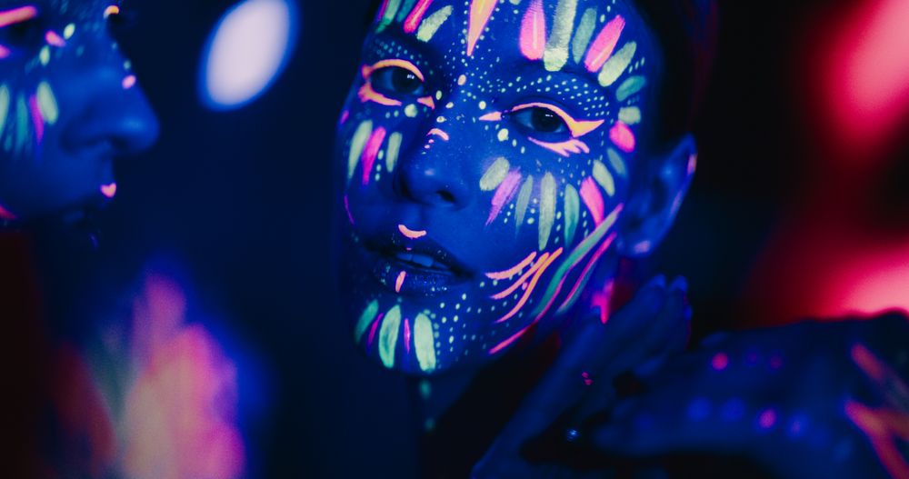 Young Sensual Model Poses with Grace and Poise, Her Vivid Body Paint Complementing Dark Abstract Background and Distorted Mirror Image